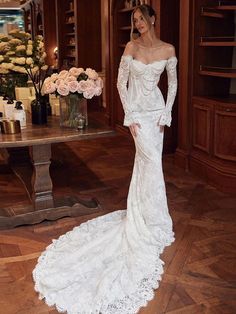 a woman in a white wedding dress standing next to a table with flowers on it