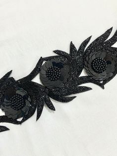 two black metal flowers on a white shirt with holes in the center and one flower has been cut out to look like leaves