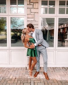 a man and woman are kissing in front of a store window with large glass windows