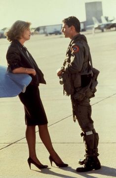 a man and woman standing next to each other in front of an airplane