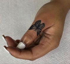 a woman's hand with a butterfly tattoo on her left thumb and ring finger