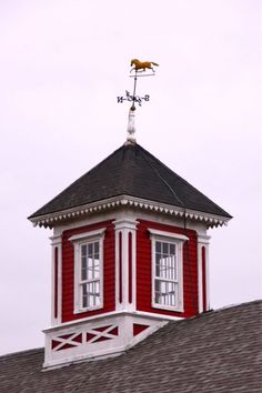 a red and white building with a weather vane on top