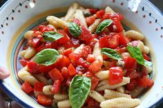 a pie with tomatoes, mozzarella and basil on top sitting on a cutting board