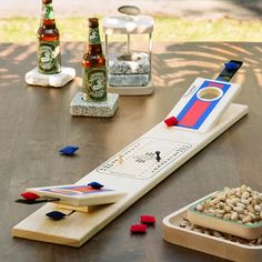 two beer bottles and a game on a table with other items in front of it