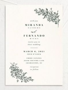 an elegant wedding card with black ink on white paper and greenery in the middle