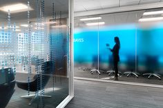 an office with glass walls and chairs in front of the wall is a blurry image of a person