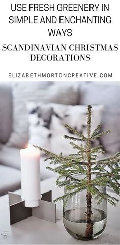 a small christmas tree in a glass vase on a table with a lit candle next to it