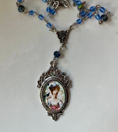 "Marie Antoinette Coeffure Cameo Glass Necklace with Blue Crystal glass bead and silver tone chain. The cameo is an art image set under glass in a vintage style antique silver bezel. The pendant length is 2\"s long and the pendant is 1 1/4\" wide. It hangs from a pressed silver tone antiqued silver Victorian style connector. The necklace is adjustable from up to 19\"s.  Will come gift boxed and will make a lovely gift." Vintage Blue Necklace With Silver Beads, Artistic Blue Beaded Jewelry, Artistic Blue Beaded Necklace, Blue Crystal Beads, Victorian Pendants, Cameo Necklace, Marie Antoinette, Glass Necklace, Victorian Style