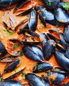 mussels are being cooked in a red sauce