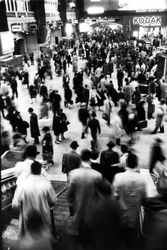 black and white photograph of many people walking down the street