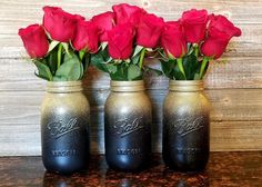 three vases with roses in them sitting on a counter top next to a wooden wall