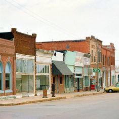 an empty street with old buildings and cars parked on the side