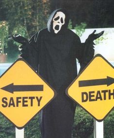 a man in a ghost costume standing next to two road signs that say east coast and west coast