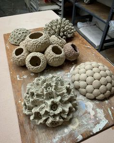 three clay sculptures sitting on top of a wooden table next to other pottery items and tools