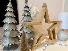 three wooden christmas trees on a table next to a lamp