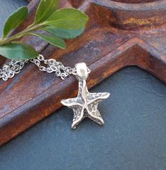 "A rustic starfish pendant, perfect for layering. The pendant is Greek cast metal with a matte pewter finish and nice detail. It hangs on a small cable link rhodium plated chain, which looks great with the antiqued effect of the pendant. The chain has a bit of sparkle to it and closes with an antiqued silver plated lobster clasp. Rhodium is a noble metal of the platinum group, known for its durability and resistance to tarnish and corrosion. The pendant is lightweight, so great for all day wear. Necklace Length: from 14 to 20 inches; optional 2\" extender chain Pendant Size: about 3/4\" Chain Size: dainty at 3mm by 2.2mm Your necklace will arrive gift wrapped. This necklace may also be available in copper patina: https://www.etsy.com/listing/1455682835/copper-patina-starfish-pendant-neckla Trip Moodboard, North Star Necklace, Layering Jewelry, Beach Lover Gifts, Surfer Necklace, Sea Lover, Starfish Pendant, Pewter Pendant, Star Pendant Necklace