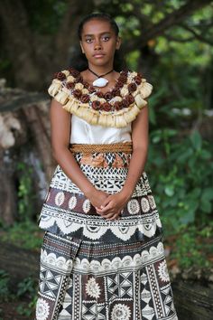 a woman in an ethnic dress standing on the ground with her hands clasped to her chest