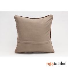 a beige pillow with red piping on the front and back, sitting against a white background