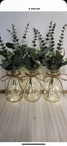 three mason jars filled with flowers and greenery