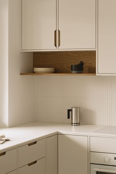 a kitchen with white cabinets and wooden shelves