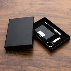 a black box with a pen, notepad and ring in it sitting on a wooden table