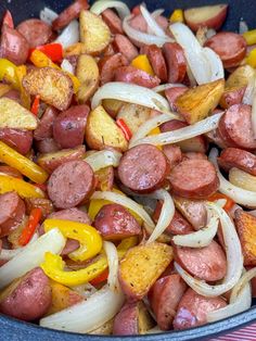 a pan filled with sausage, onions and peppers