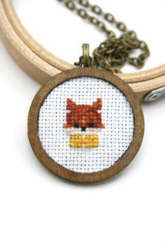 a cross stitch necklace with a woman's face on the front and back of it