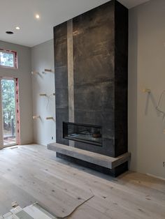 an empty living room with a fireplace in the middle and wood flooring on the other side