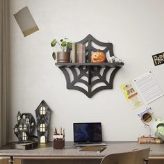 a desk with a laptop computer and some decorations on top of it, in front of a white wall