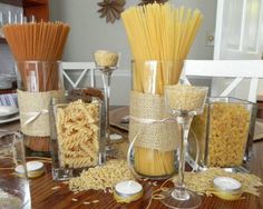 a wooden table topped with lots of different types of pasta and wine goblets