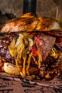 a bacon cheeseburger sitting on top of a table next to a glass of beer