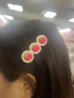 the back of a woman's head with three crocheted fruit hair clips on it