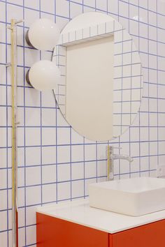 a bathroom with blue and white tiles on the wall, sink and mirror above it