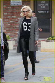 a woman walking down the street wearing black leather pants and a t - shirt with numbers on it