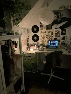 a desk with a laptop computer sitting on top of it next to a wall covered in pictures