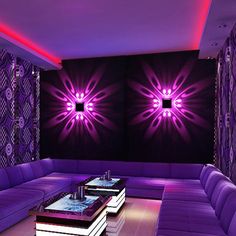 a living room with purple couches and tables in front of two wall mounted lights