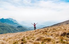 a man standing on top of a hill with his arms wide open in the air