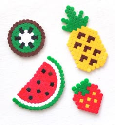 four pieces of beaded fruit on a white surface with one piece cut out to look like an apple, watermelon and pineapple