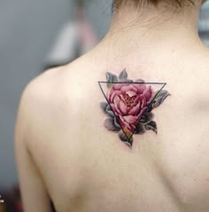 the back of a woman's neck with a rose tattoo on her left side