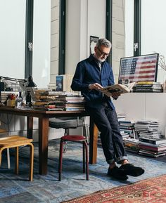 a man sitting at a table reading a book and looking at the papers in front of him