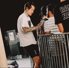 a man with tattoos on his arm standing in front of a metal barricade