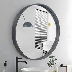 a bathroom with a round mirror above the sink and a black faucet in front of it