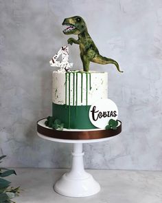 there is a cake decorated with a dinosaur on the top and green icing around it