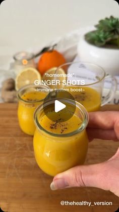 someone is holding their hand out to show how they are making ginger shots with oranges and lemons in the background