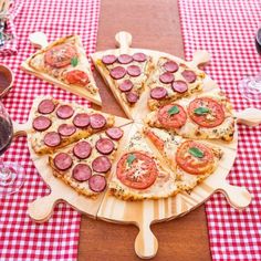 a pizza with pepperoni and tomatoes on a wooden platter next to glasses of wine