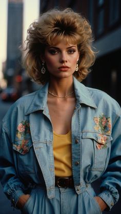 A model embodying the fashion of the 80s with an embroidered denim jacket, bold makeup, and voluminous hairstyle. Casual 80s Fashion, 80s Vs 90s Fashion, Women’s 80s Fashion, Retro Denim Outfits, 80 Costume Ideas For Women, 80's Costume Ideas, 80s Retro Outfit Ideas, Super8 Camera