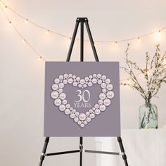 an easel with a 30th birthday card on it next to a vase and string lights