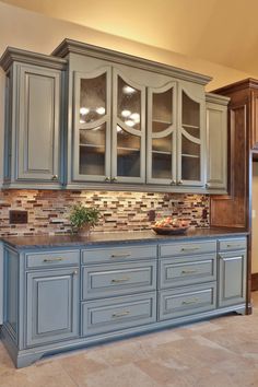 a kitchen with blue cabinets and tile backsplash in the center, along with marble counter tops