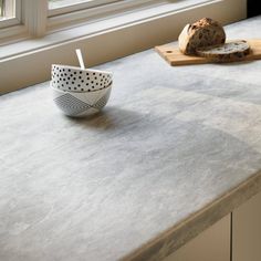 a bowl on a counter next to a loaf of bread