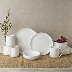 a table topped with white dishes and cups